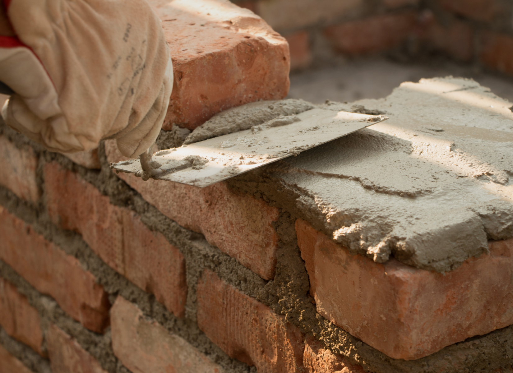 Bricklaying with trowel and mortar in progress.